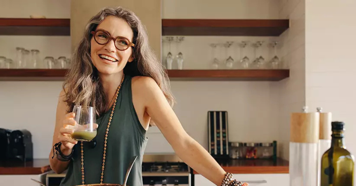 woman holding glass with green juice